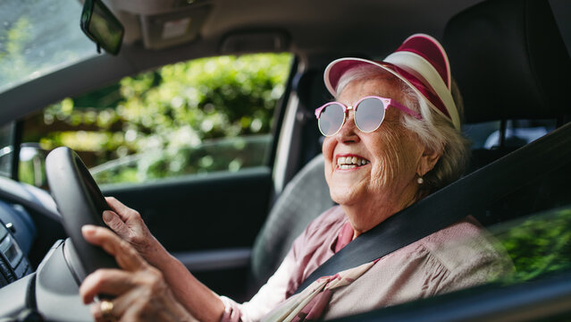 Happy senior woman driving car alone, enjoying car ride. Safe driving for elderly adults, older driver safety.