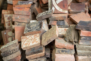 Ensemble de briques de forme carrée, fabriquées avec de la terre, de la paille et de la chaux. Décorées de symboles, de fleurs, de lettres et d'animaux. Château de Guédelon, France.