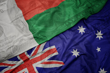 waving colorful flag of madagascar and national flag of australia on the dollar money background. finance concept.