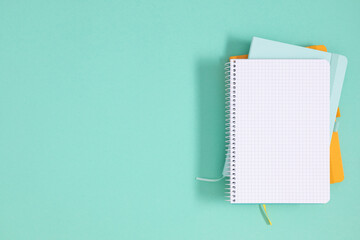 Back to school concept. Flat lay top view of stack of notepads, isolated on pastel mint background. 