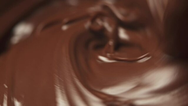Melted chocolate nut nougat pours from above forming a beautiful pattern. Chocolate dessert close-up.