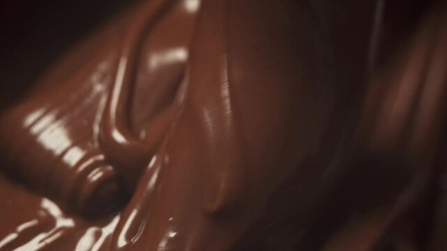 Melted chocolate nut nougat pours from above forming a beautiful pattern. Chocolate dessert close-up.