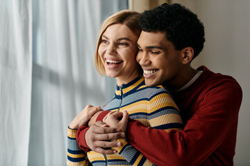 A happy interracial couple shares a tender embrace in their modern apartment, filled with joy and laughter.