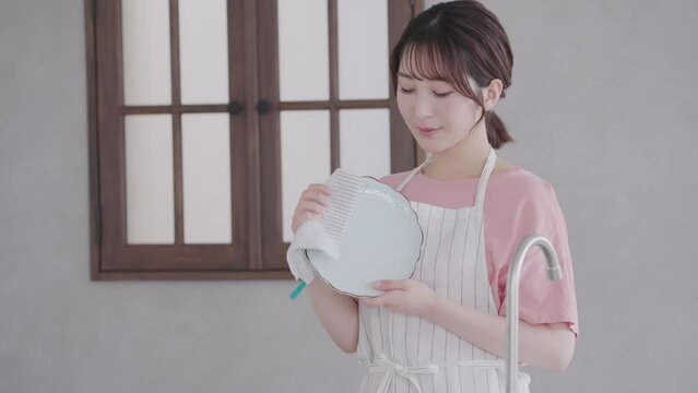 キッチンで皿拭きをする女性（家事・主婦）