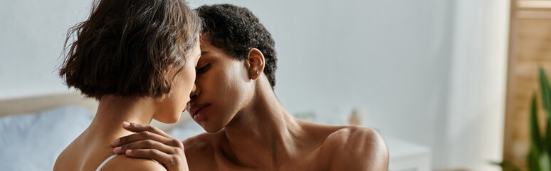 A young Asian woman and a Black man are embracing and kissing on a bed.