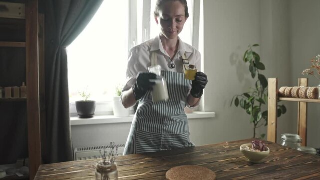 Female soap maker chooses the ingredients to create a milky honey soap. Creating handmade natural soap.