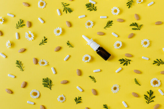 Pills and capsules with chamomile flowers on yellow background