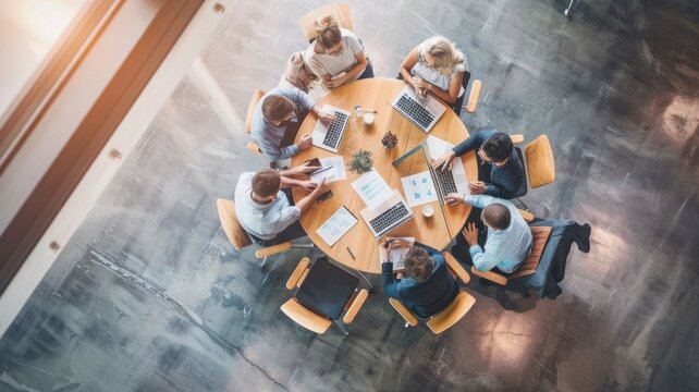 High-angle shot of professionals having a corporate meeting around a circular table in a modern office. AIG53M
