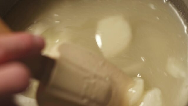 Person mixes the soap mass in the process of making soap. The master mixes the ingredients in the workshop