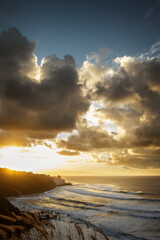 Sunset on the coast, golden clouds at sunset over the sea agitated by the waves and fishing village in the background. Big clouds in the sky. Paradise. Sky. Tenerife, canary islands spain