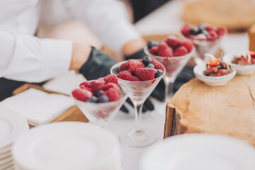 hands of a waiter prepare food for a buffet table in a restaurant. caterer arranges array of appetizers on a serving table. professional catering event with an emphasis on presentation and variety.