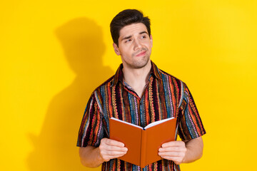 Portrait of nice young man book look empty space wear shirt isolated on yellow color background