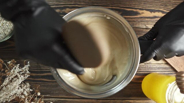 Person mixes the soap mass in the process of making soap. The master mixes the ingredients in the workshop.