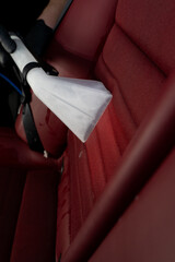 Removing dirt from car seat with the help of special hoover nozzle. Detailing auto seat using...