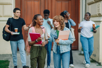 Diverse college students exiting university building and going on break