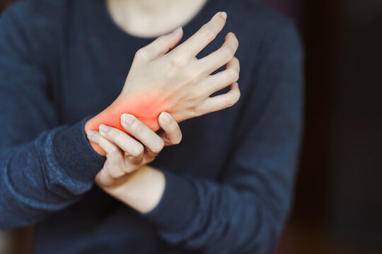 Person holding wrist in pain, highlighting wrist pain and discomfort. Concept of injury, arthritis, or carpal tunnel syndrome.