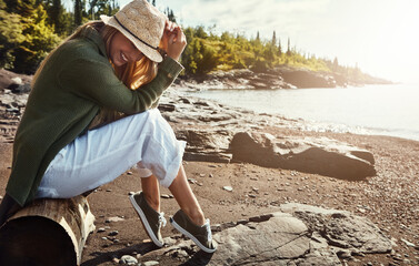 Laugh, relax and woman on beach with hat, island holiday and fun outdoor adventure in tropical nature. Travel, ocean and girl on weekend vacation with water, smile and happy morning on coast in Italy