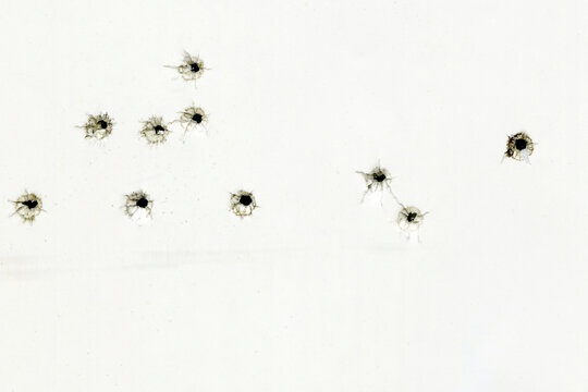 Bullet holes on a white sheet of paper, gunshot damage, abstract background.
