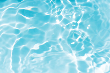 Blue water with ripples on the surface. Defocus blurred transparent blue colored clear calm water surface texture with splashes and bubbles. Water waves with shining pattern texture background.