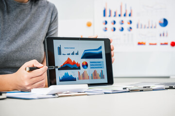 A businesswoman works diligently at her desk, reviewing financial documents and analyzing investment data. She ensures accuracy and efficiency in financial calculations and audit processes.