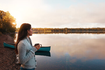 Morning, smile and woman with coffee in river, sunrise and happy in nature for vacation and outdoor. Break, writer and girl thinking of ideas in countryside of Finland with peace and holiday in lake