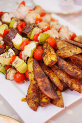 Rustic potatoes and vegetable kebabs on the grill on the banquet table. appetizers for a buffet table. catering services for the event.