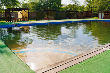 The dirty swimming pool outside. Cleaning of the water and pool before the opening of the flying swimming season.