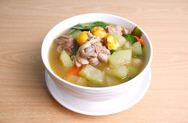 Thai Chicken Curry with Winter Melon in white bowl on brown wooden table background.Thai food