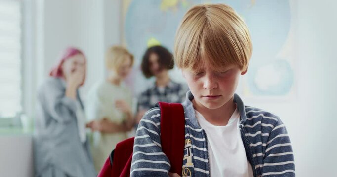 Group of students bullying their peer. Laughing at boy during school. Child looking behind at group. Feeling sad and disappointed. Feeling pressure from peers. Feeling left behind.