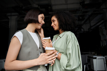 A lesbian couple enjoys a coffee break at work, sharing a warm moment together.