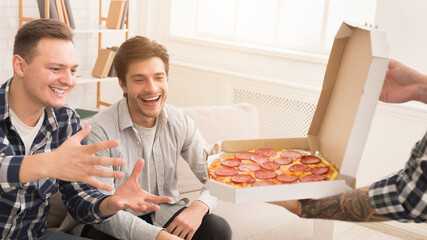 Friends taking slices of hot pizza from delivery box, having home party