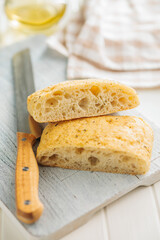 Italian ciabatta bread on cutting board on white table.