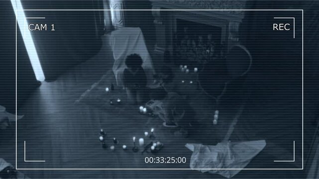Overhead CCTV shot of three teens sitting on floor among lit candles and reading incantations from occult book, invoking dark forces who live in dark desolate mansion