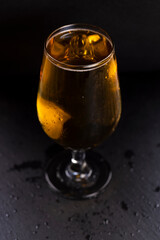 light golden beer in a glass glass on a black background