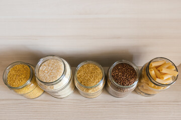 A row of glass jars filled with various types of food.  View from above.