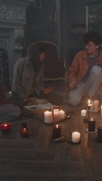 Vertical side shot of girl being demonized during invocation ritual in smokey dark house and diverse frightened friends trying to help