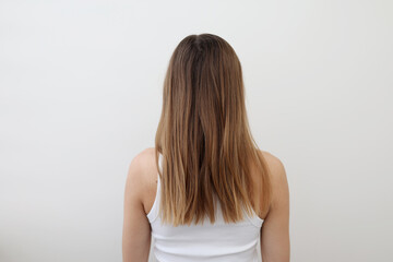 Obraz premium Rear view of woman with long but problematic hair, unhealthy, messy, damaged, isolated on background. Girl problem hair-type back view. Spit ends dry over-brushing hairstyle. Beauty care concept.