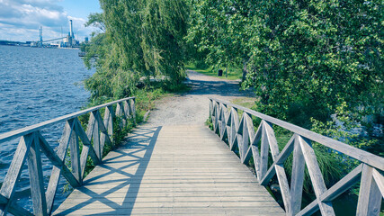 wooden bridge, winding bridge, brown bridge, green trees, lush trees, blue sky, peaceful...