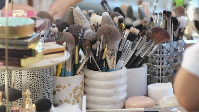 Big lush brush gains powder, bronzer and highlighter on pile to be used in make-up. Artist working with face palette. Details of working process, tools in beauty industry. Decorative cosmetics.