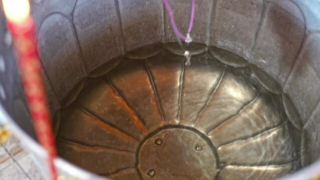 The priest's hand holds the cross on a chain and dips it into the holy water in the baptismal font. The Sacrament of Baptism in the Orthodox Church.