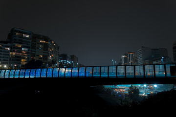 Bridge with a blue light shining on it, Miraflores, Lima Peru. City skyline in the background