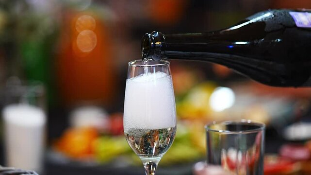 White sparkling wine is poured into a glass on the banquet table. alcoholic and soft drinks for the celebration. work as a sommelier or waiter. champagne