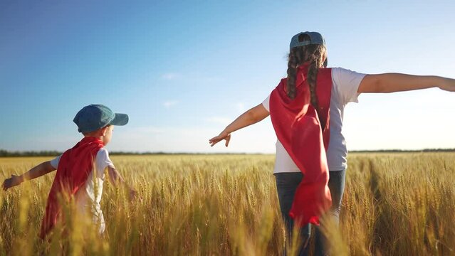 A group of kids playing a video game of superheroe together. Child hero fun concept. Superhero running through the wheat with children. sunset A group of kids playing a game of running together.