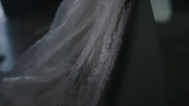No people tilt shot of chair covered with polyethylene in dark room of forsaken house