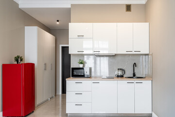 stylish interior of apartment with modern kitchen in white. kitchen design with appliances, microwave, red refrigerator, stove. 