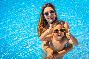 Happy mother and boy inside a blue pool water