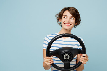 Young minded happy woman wears striped t-shirt casual clothes hold steering wheel driving car look...