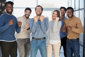 Fototapeta premium Group of happy managers rejoice at a successful deal by clenching their hands into fists and raising them up