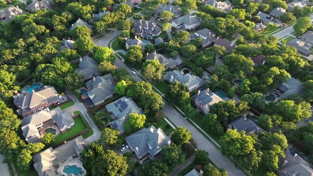 Lush greenery affluent neighborhood tree lined street along row of large two-story residential houses, expensive suburban homes with swimming pool North of Dallas Fort Worth metroplex, flyover. USA 