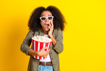 Photo of terrified girl with perming coiffure wear khaki shirt in 3d glasses hold popcorn watch horror isolated on yellow color background